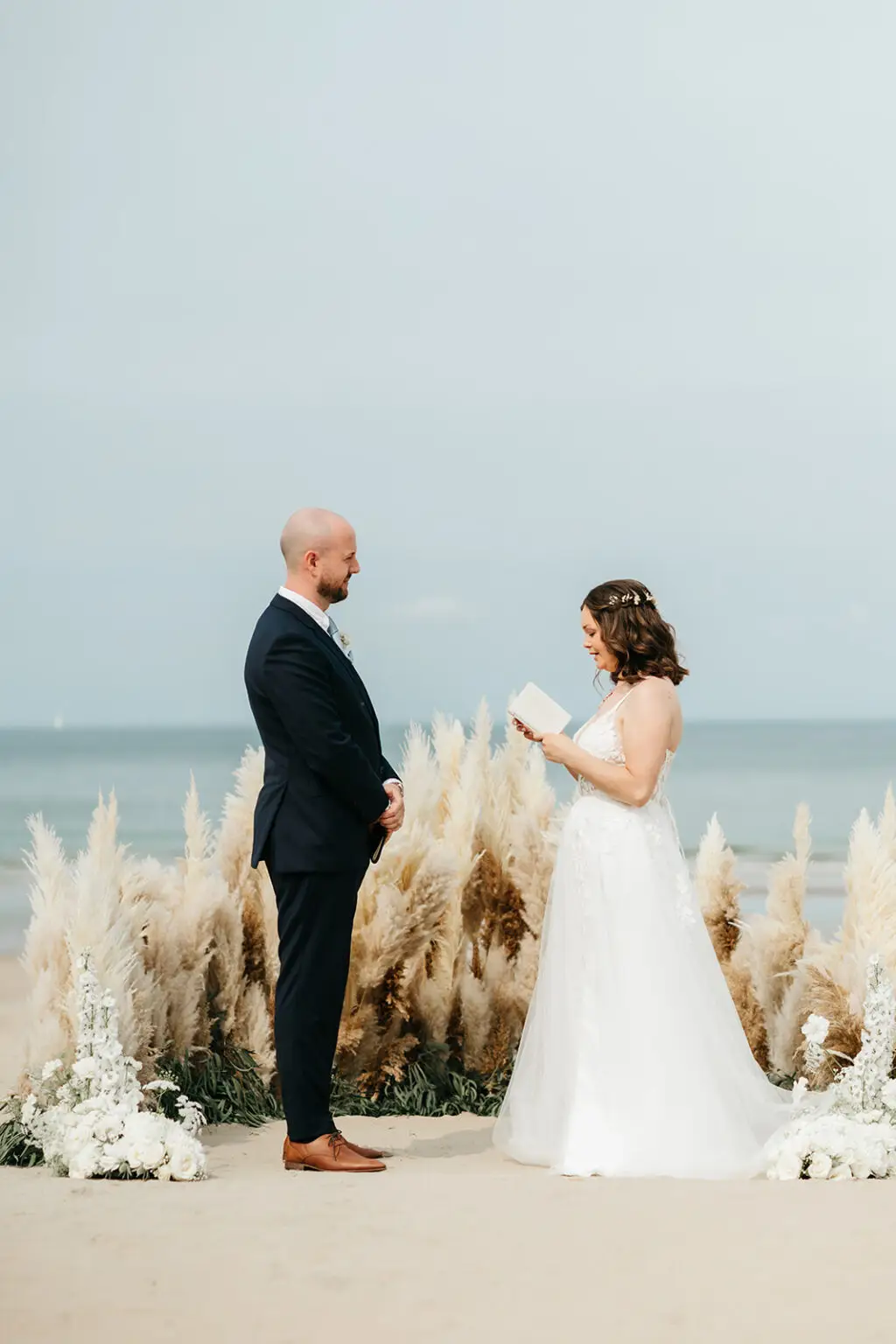 Bride reading vows during a beach elopement near Amsterdam with ocean view and pampas grass decor