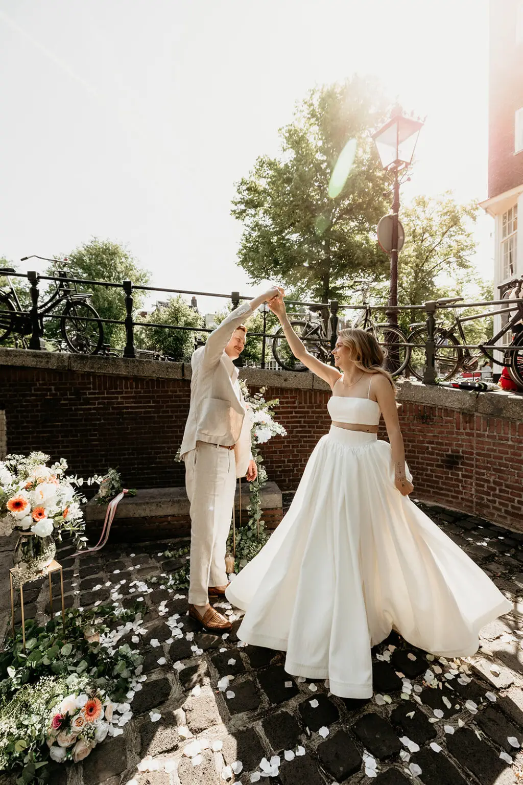 Couple dancing during an intimate elopement in Amsterdam under a canal bridge with floral setup