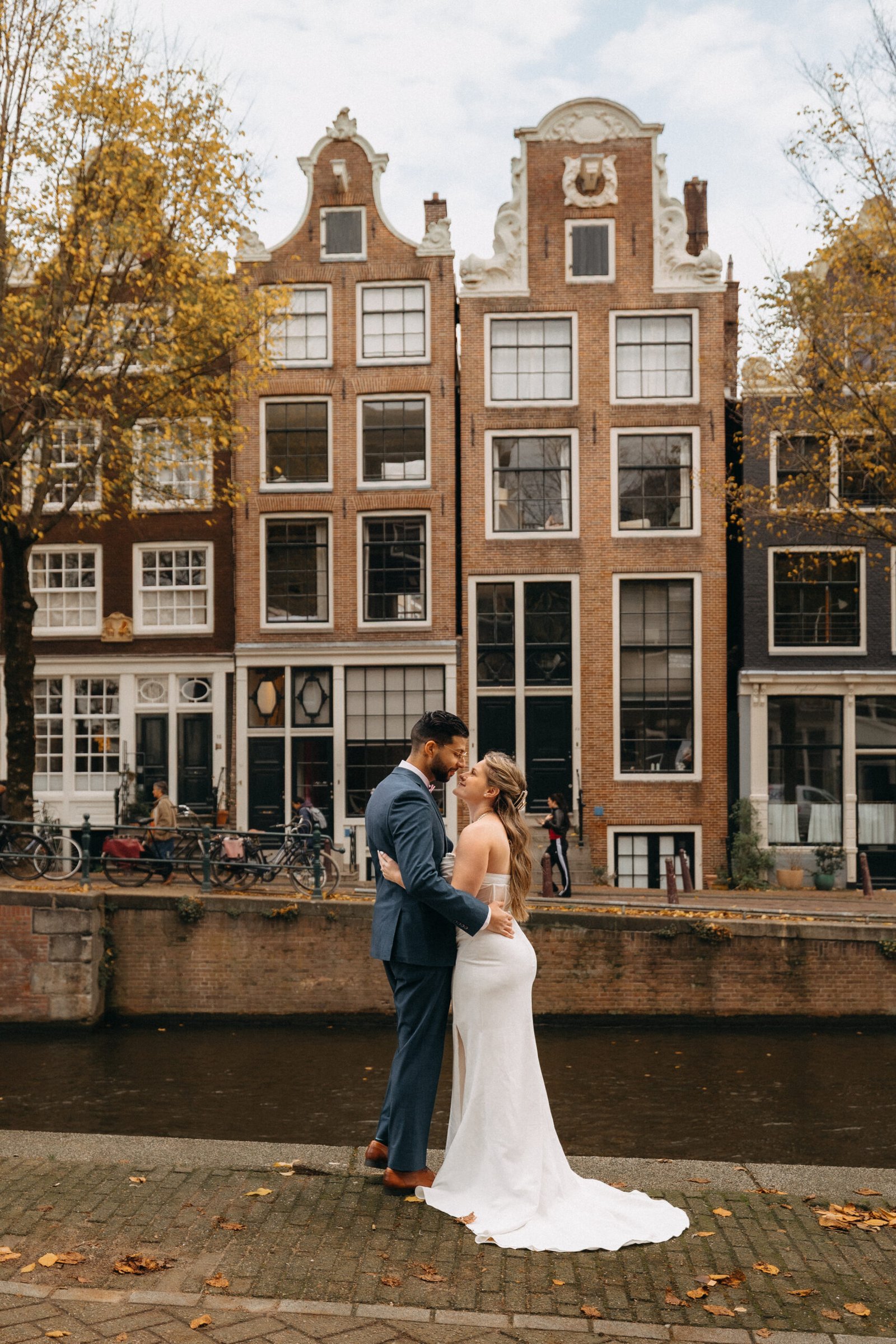 Wedding couple standing in front of an Amsterdam canal with historic Dutch houses in the background