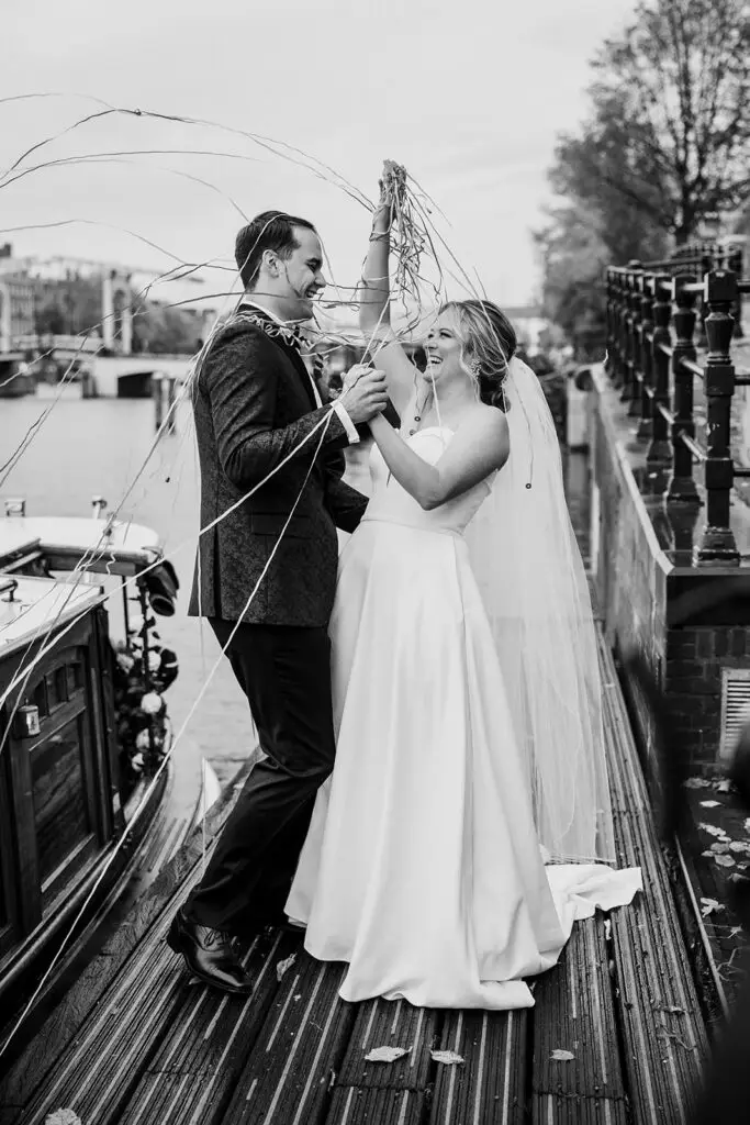 Bride and groom celebrating beside an Amsterdam canal after their intimate elopement ceremony