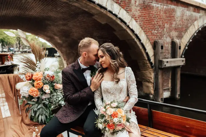 Couple sitting on a decorated canal boat during a romantic Amsterdam elopement photoshoot