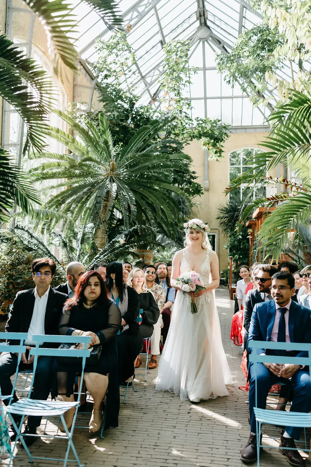 Bride walking down the aisle inside a greenhouse during a botanical garden wedding in Amsterdam