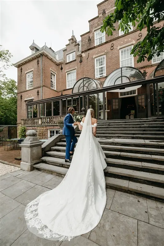 Couple walking up the steps of Kasteel de Wittenburg during an elegant wedding near Amsterdam