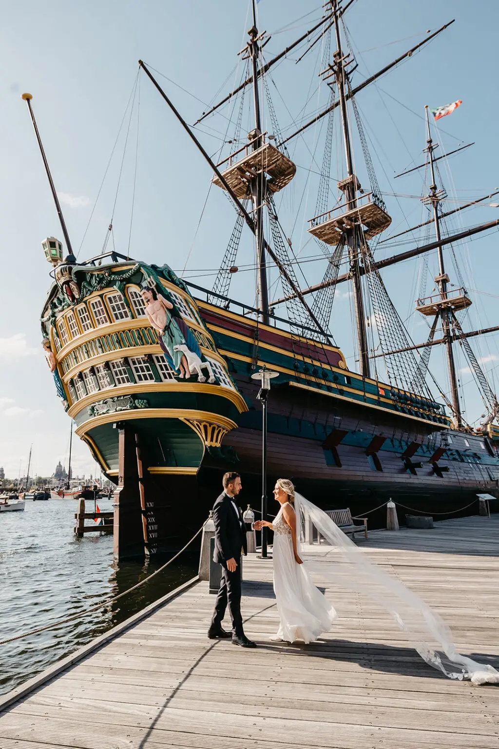 Couple standing by a historic ship on the waterfront during an elopement in Amsterdam