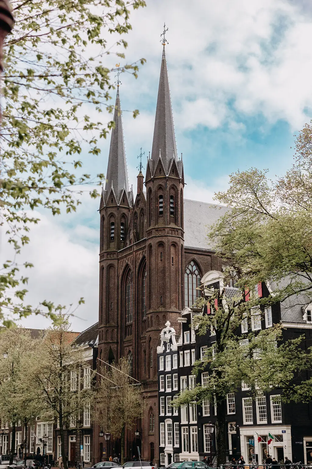 Historic De Krijtberg church building in Amsterdam with tall towers and canal houses in the city center