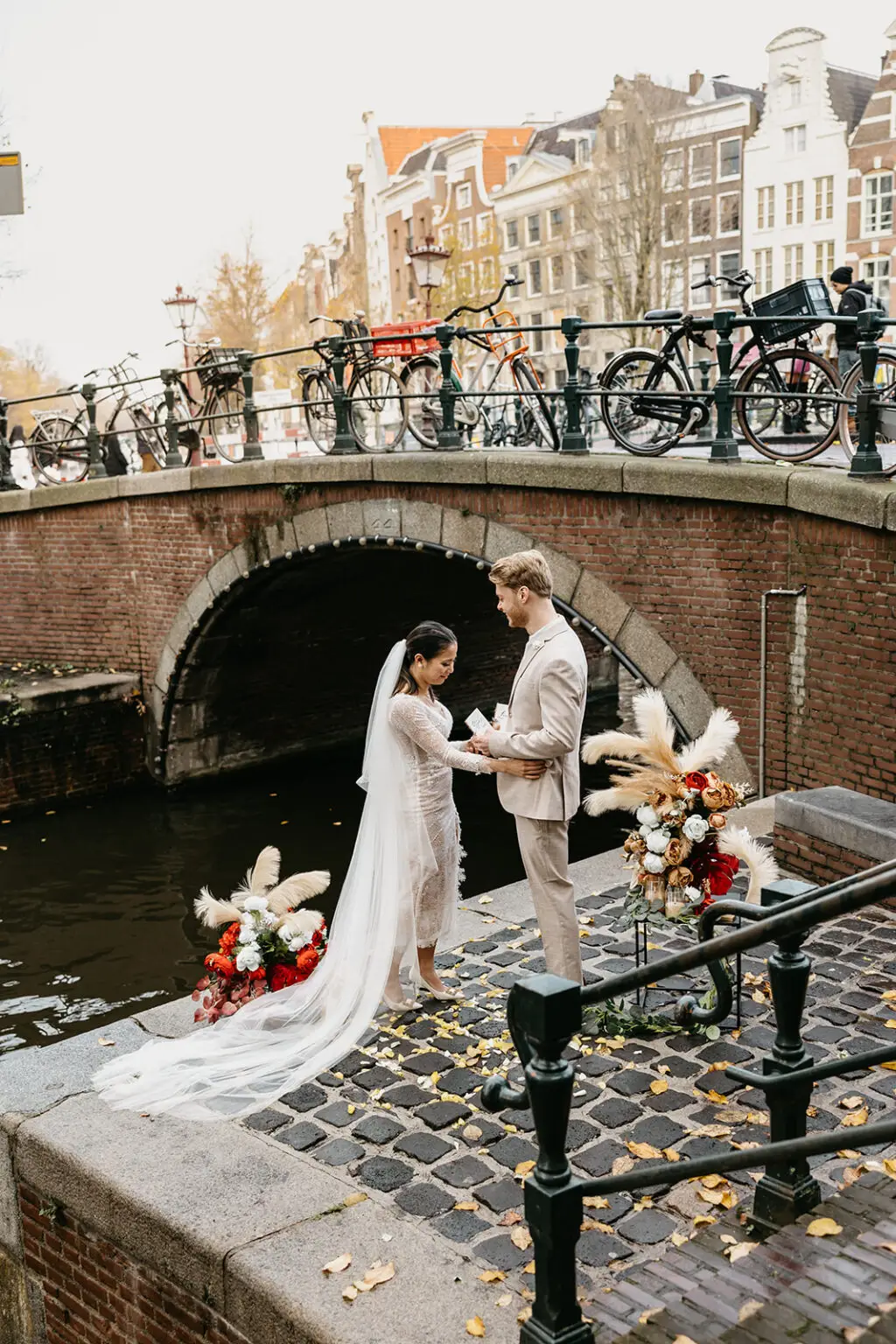 Couple exchanging vows during a canal-side elopement ceremony in Amsterdam with floral styling and historic bridge