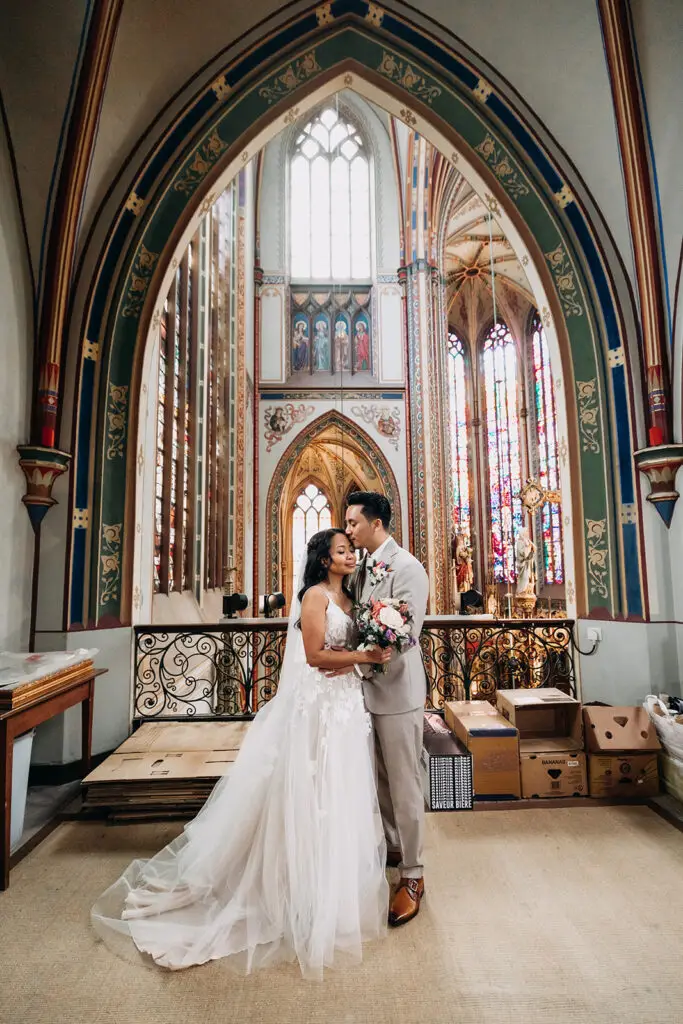 Couple embracing inside De Krijtberg church during an intimate elopement in Amsterdam