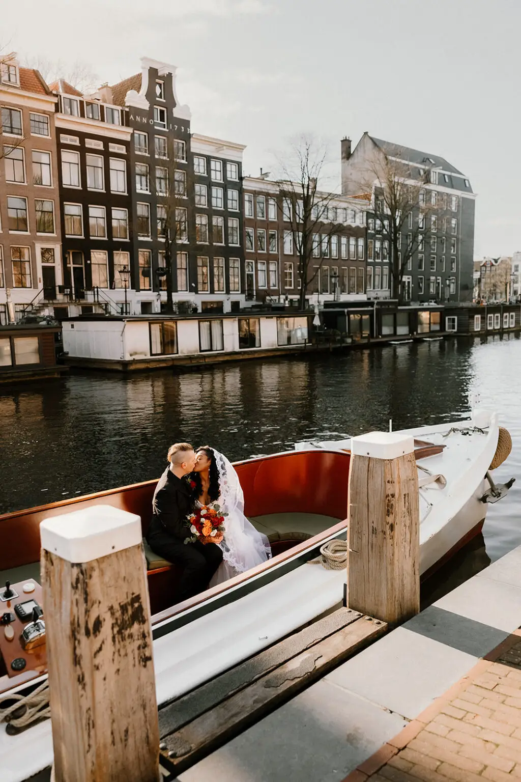 Couple kissing on a small boat along Amsterdam canals during an intimate elopement