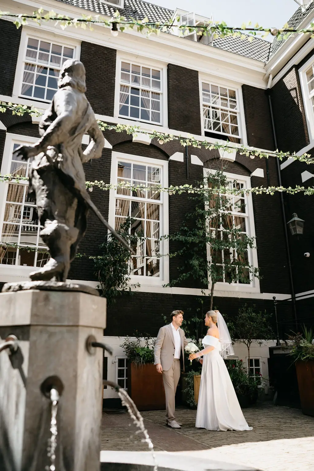 Couple standing in a historic courtyard in Amsterdam during an intimate elopement with classic architecture