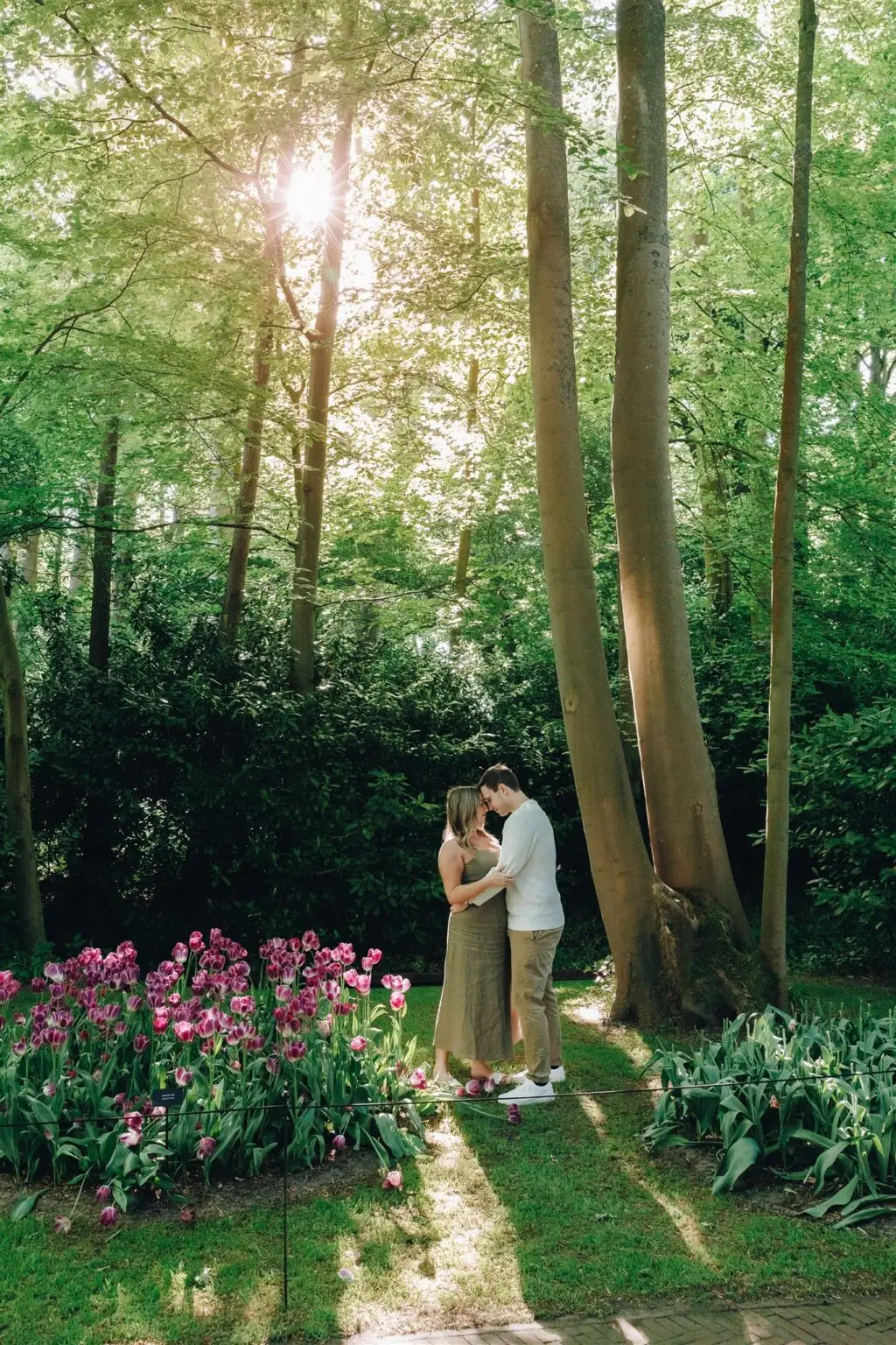 Couple standing together in a peaceful garden surrounded by tulips and trees near Amsterdam