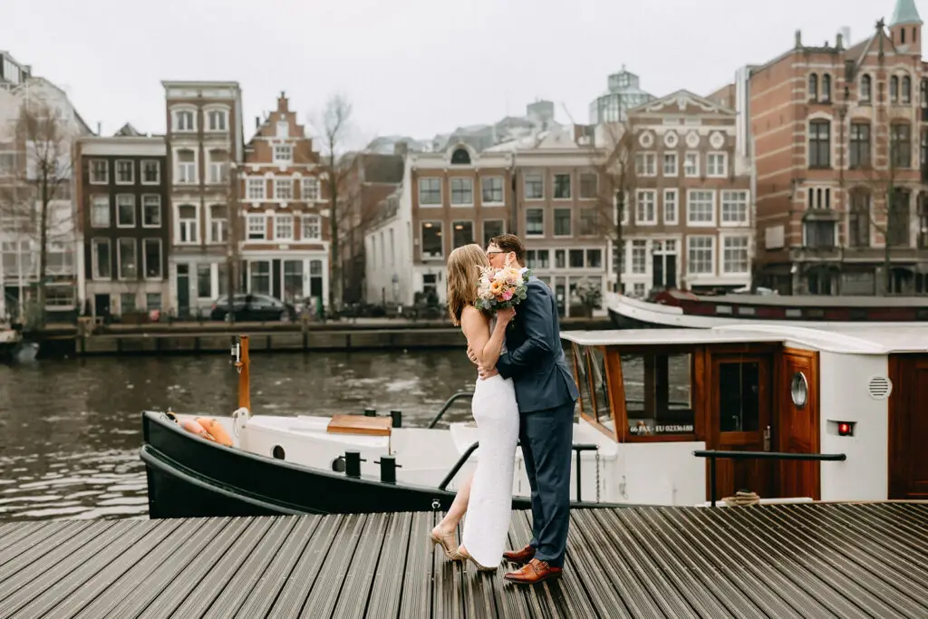 Couple kissing by a private boat on Amsterdam canals during an intimate elopement