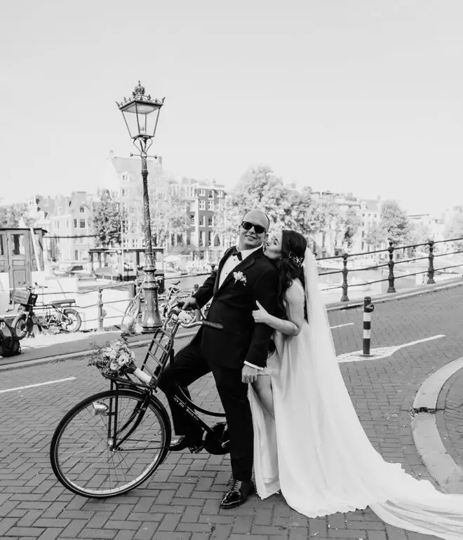 Couple kissing beside a bicycle on an Amsterdam canal bridge during an intimate city elopement