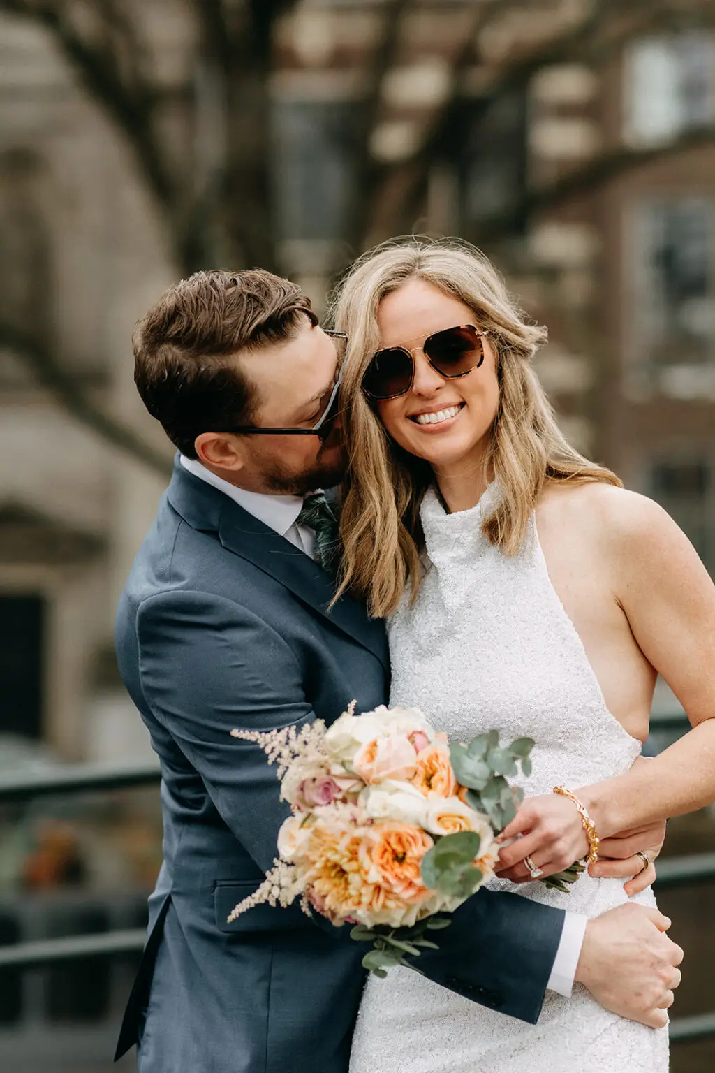 Kristin and Logan embracing during their Amsterdam wedding photoshoot while holding a spring bridal bouquet