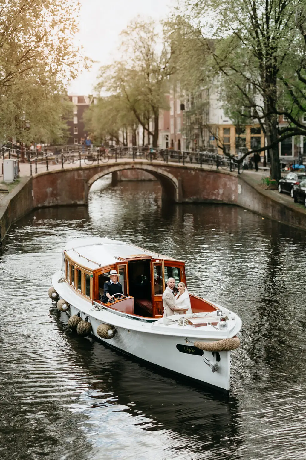 Couple cruising through Amsterdam canals on a private wedding boat after their ceremony