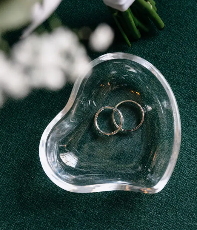 Wedding rings in a heart-shaped glass dish during an Amsterdam elopement ceremony