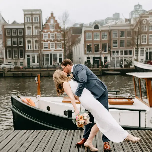 Kristin and Logan sharing a kiss beside their private canal boat on the Amsterdam waterfront during their March wedding