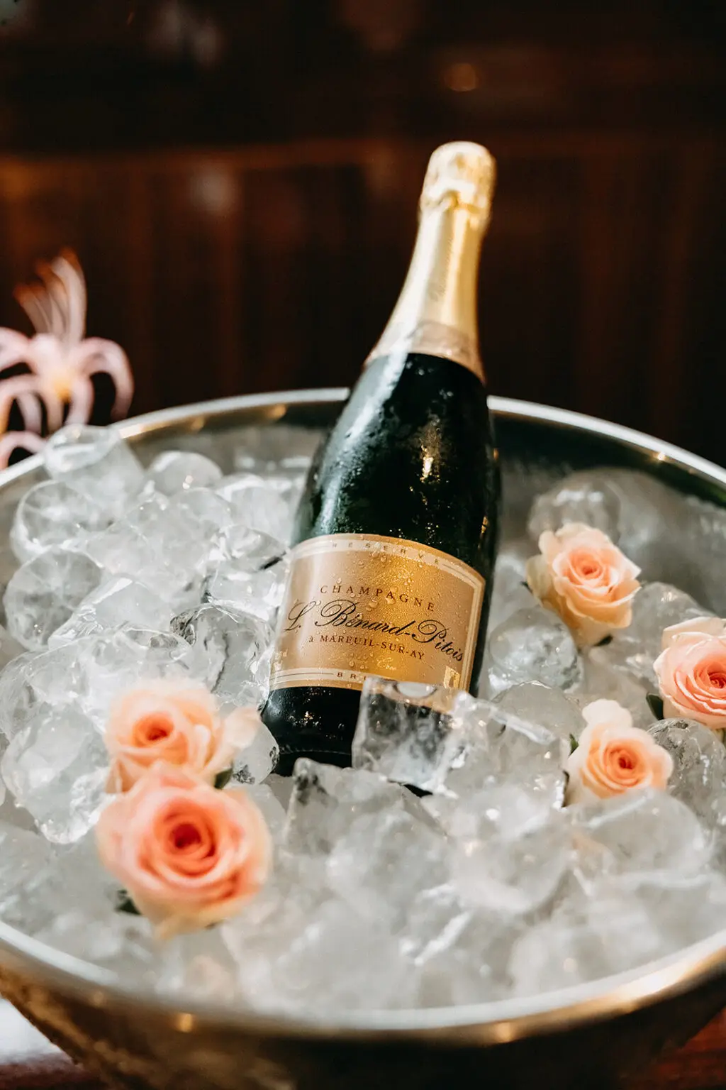 Champagne bottle chilled on ice with blush roses during a private canal boat wedding in Amsterdam