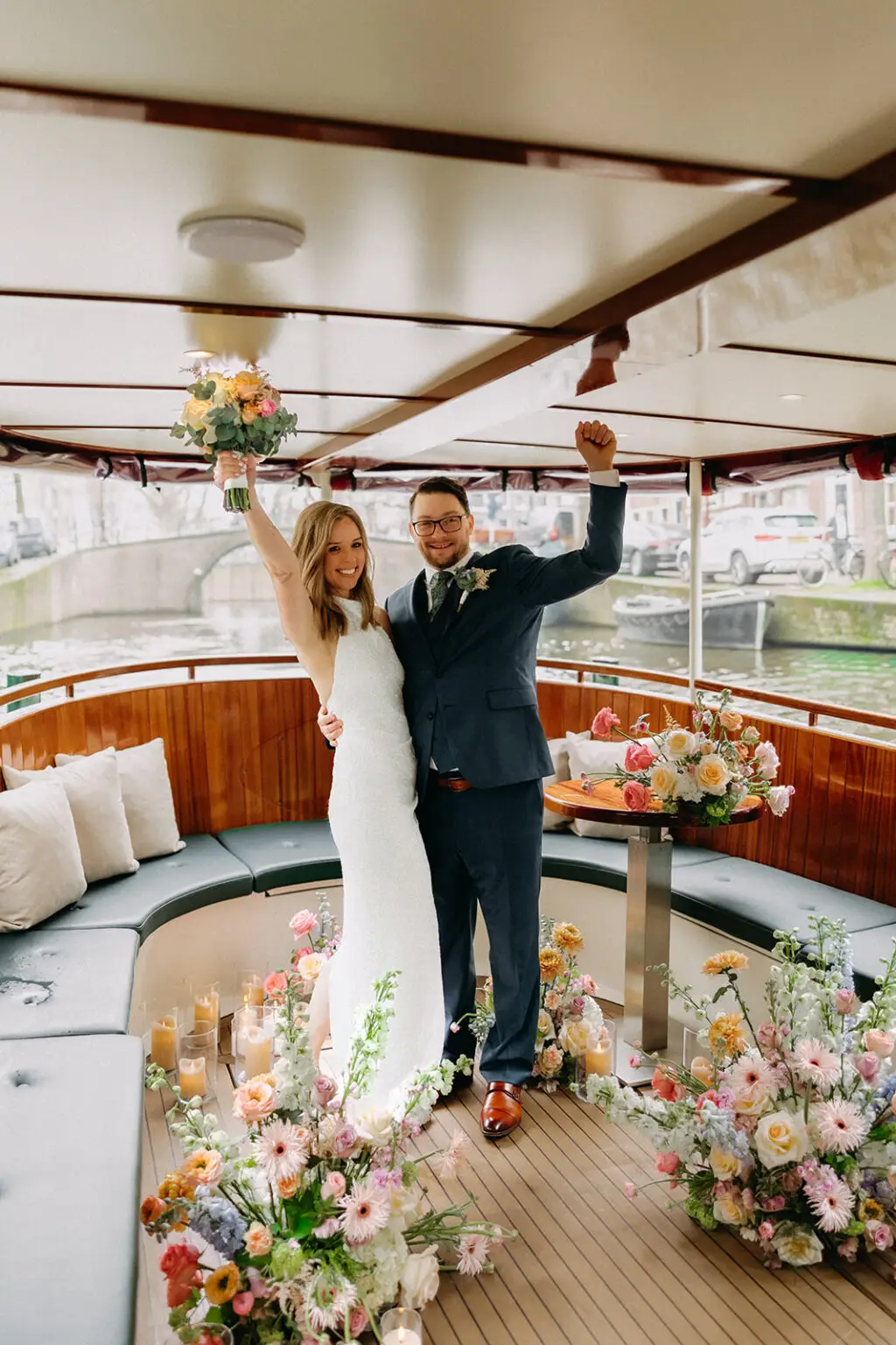 Kristin and Logan celebrating after their ceremony inside a flower-filled canal boat in Amsterdam