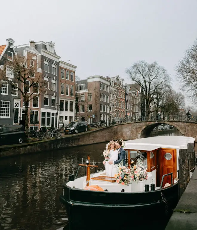 Private canal boat decorated with flowers cruising through Amsterdam canals during a March wedding