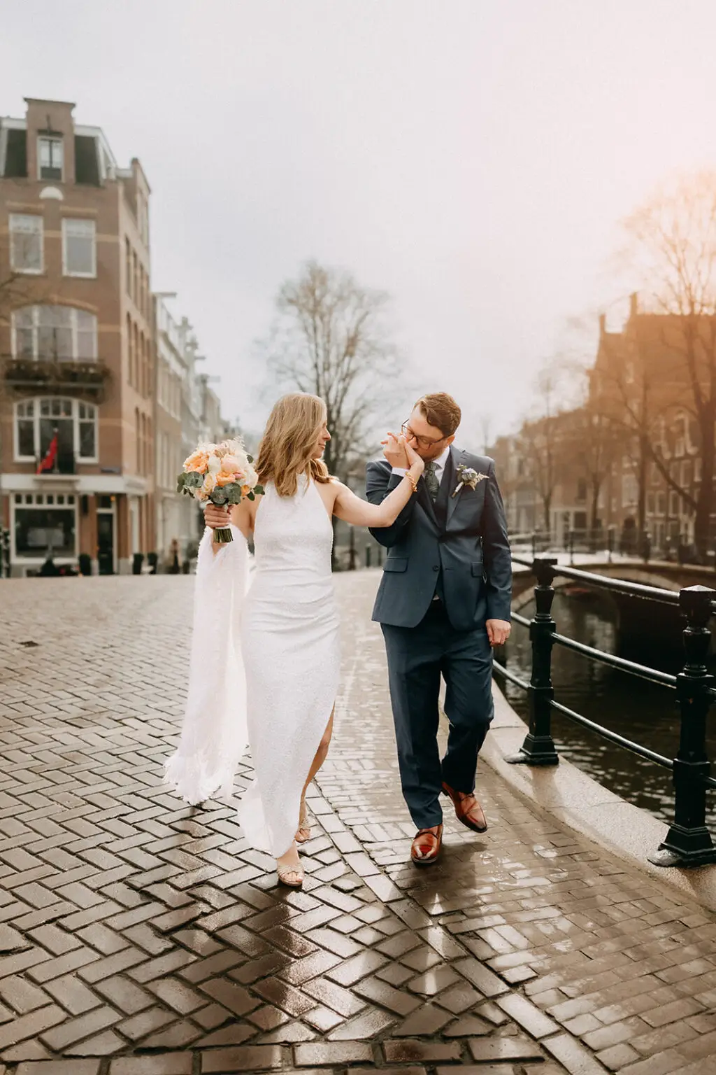 Kristin and Logan walking hand in hand beside an Amsterdam canal after their private wedding ceremony