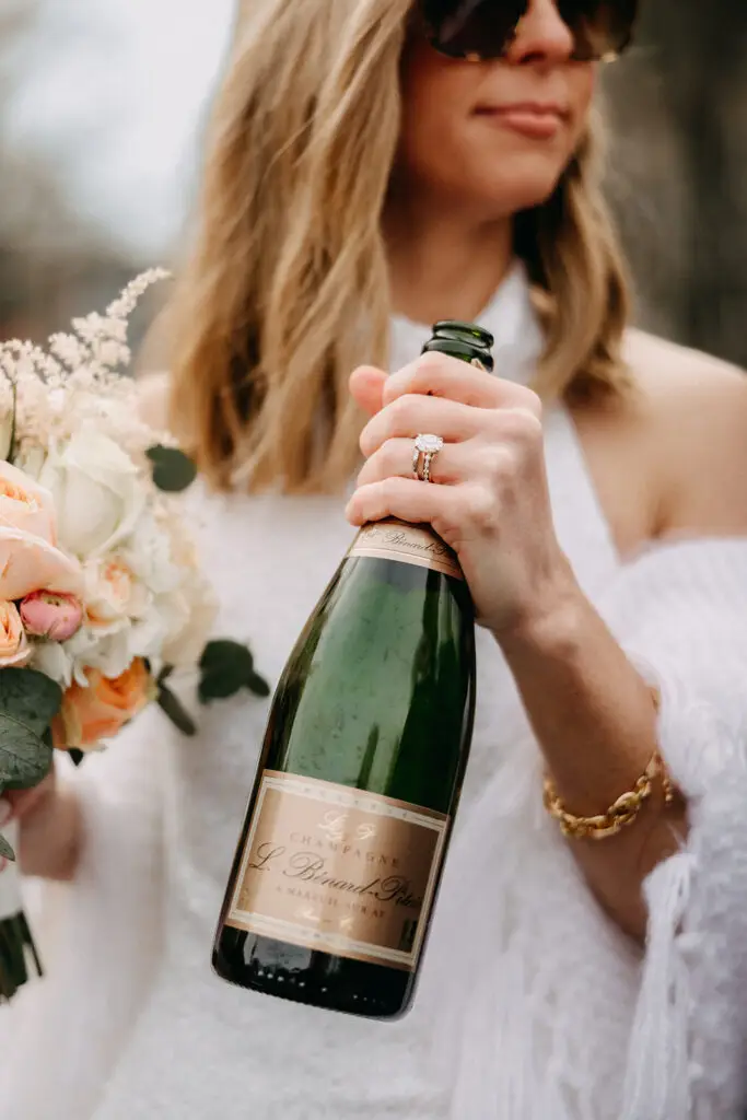 Bride holding a champagne bottle and wedding bouquet during a spring wedding photoshoot in Amsterdam