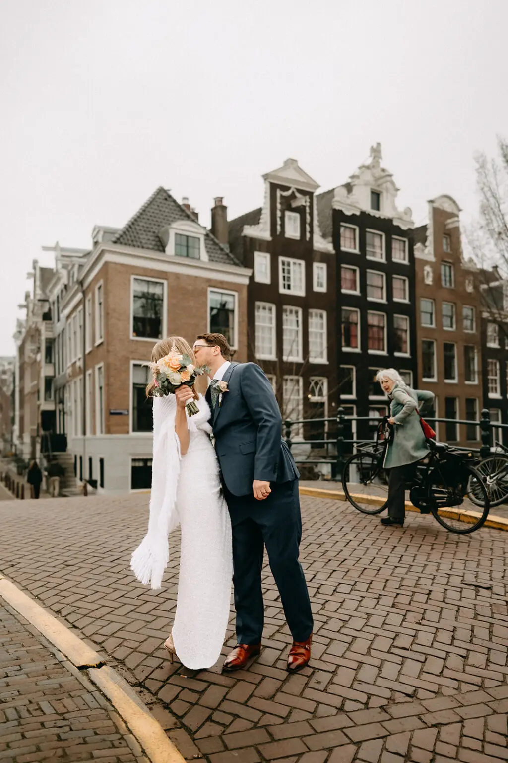 Kristin and Logan kissing on a historic Amsterdam canal bridge during their wedding photoshoot