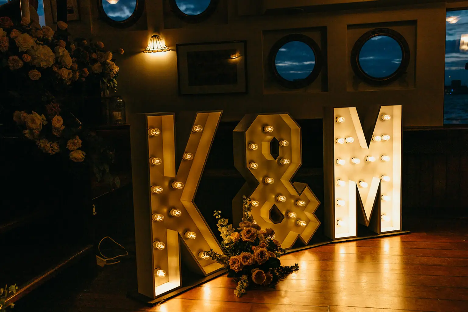 Illuminated wedding initials displayed inside a private Amsterdam canal boat during a destination wedding reception