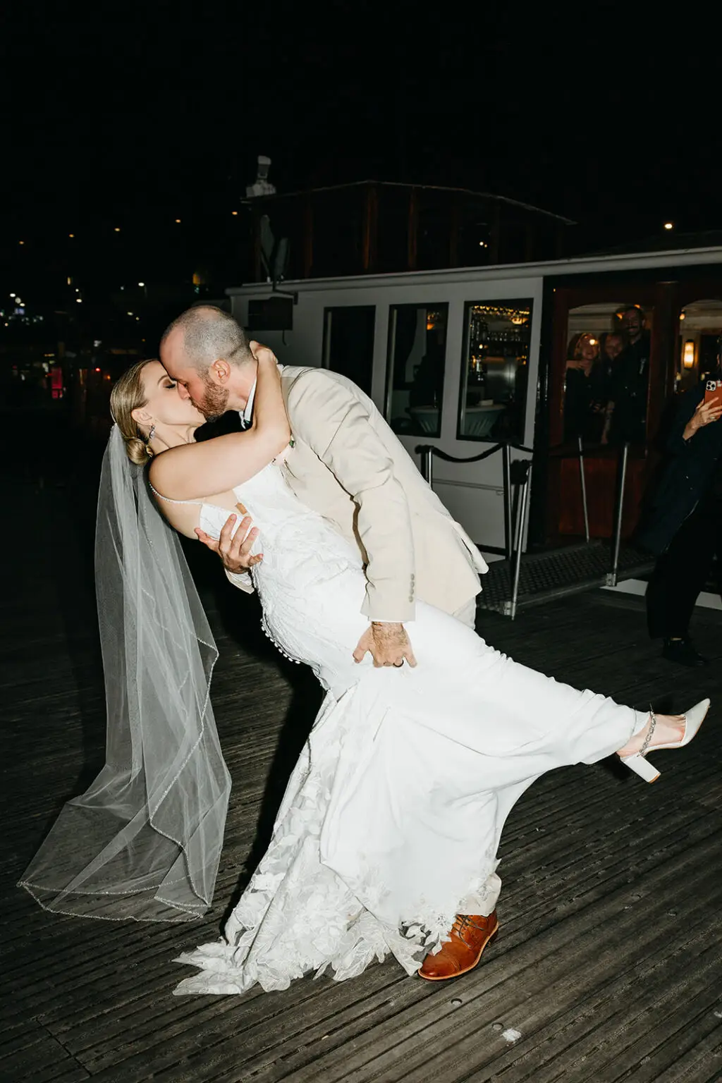 Bride and groom sharing a romantic kiss beside their wedding boat after an Amsterdam destination wedding