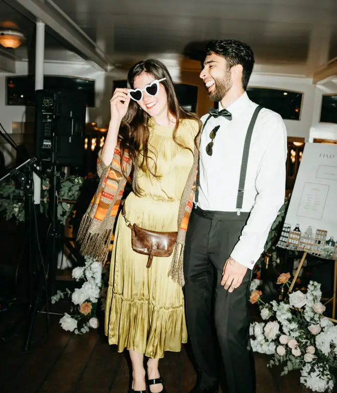 Wedding guests posing with photo booth props during a destination wedding reception aboard an Amsterdam canal boat