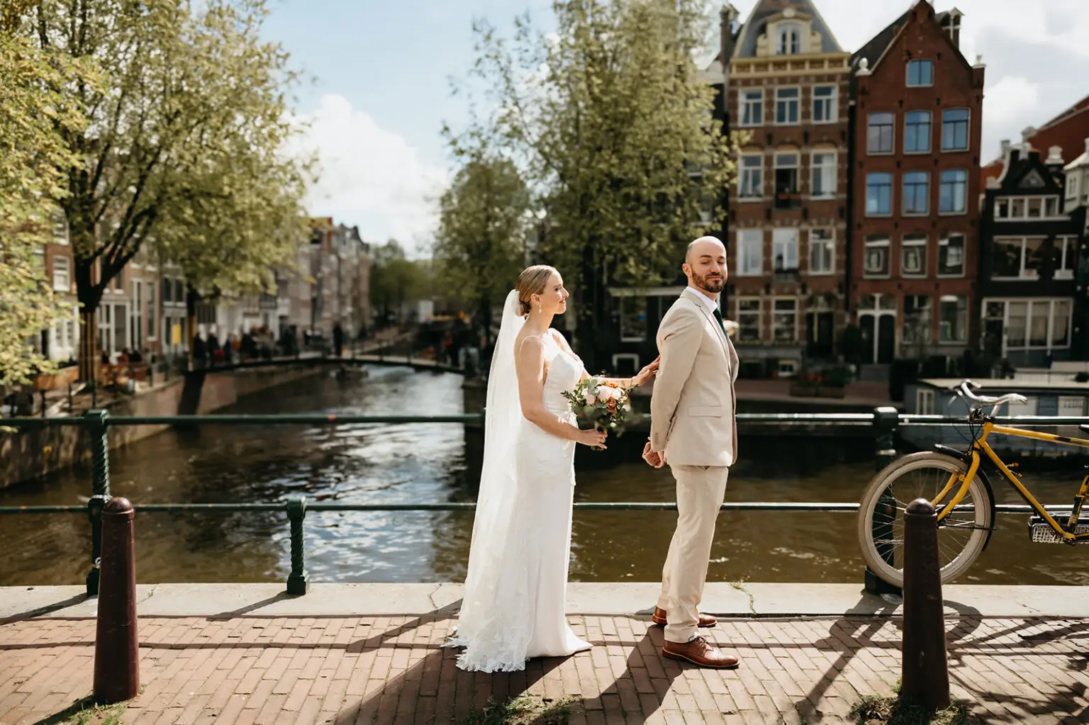 Bride and groom sharing their first look beside Brouwersgracht with historic Amsterdam canal houses in the background