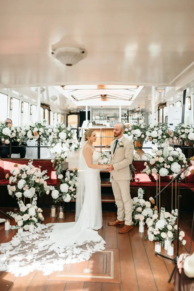Bride and groom exchanging vows surrounded by florals aboard Het Wapen van Amsterdam