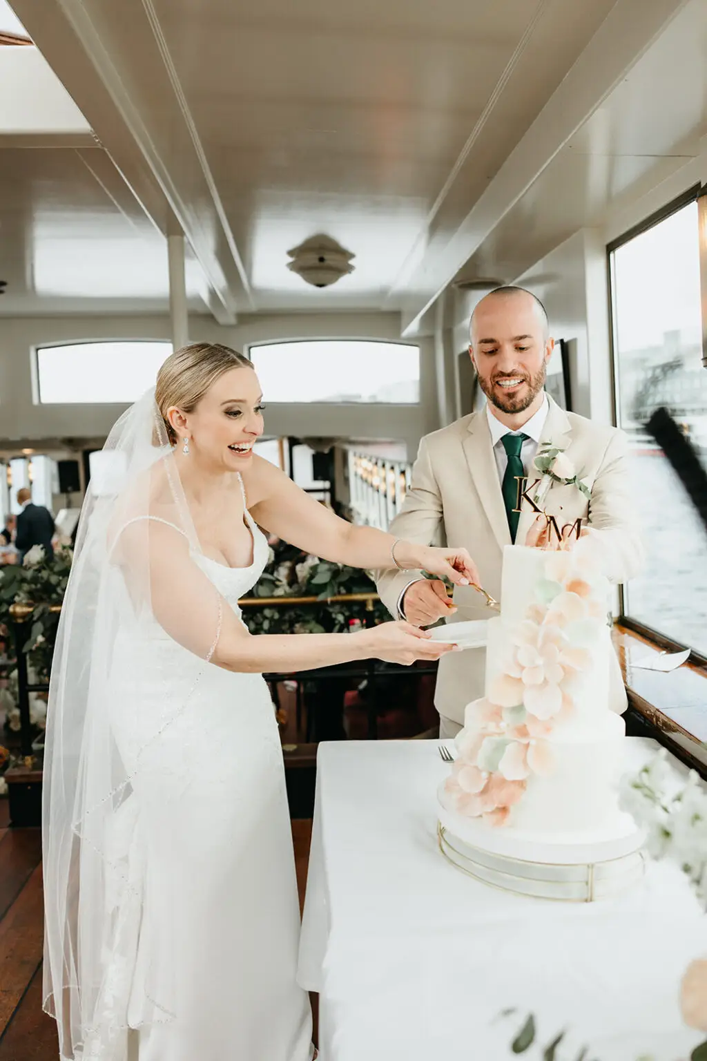 Newlyweds smiling while cutting their wedding cake during an Amsterdam destination wedding reception on a canal boat