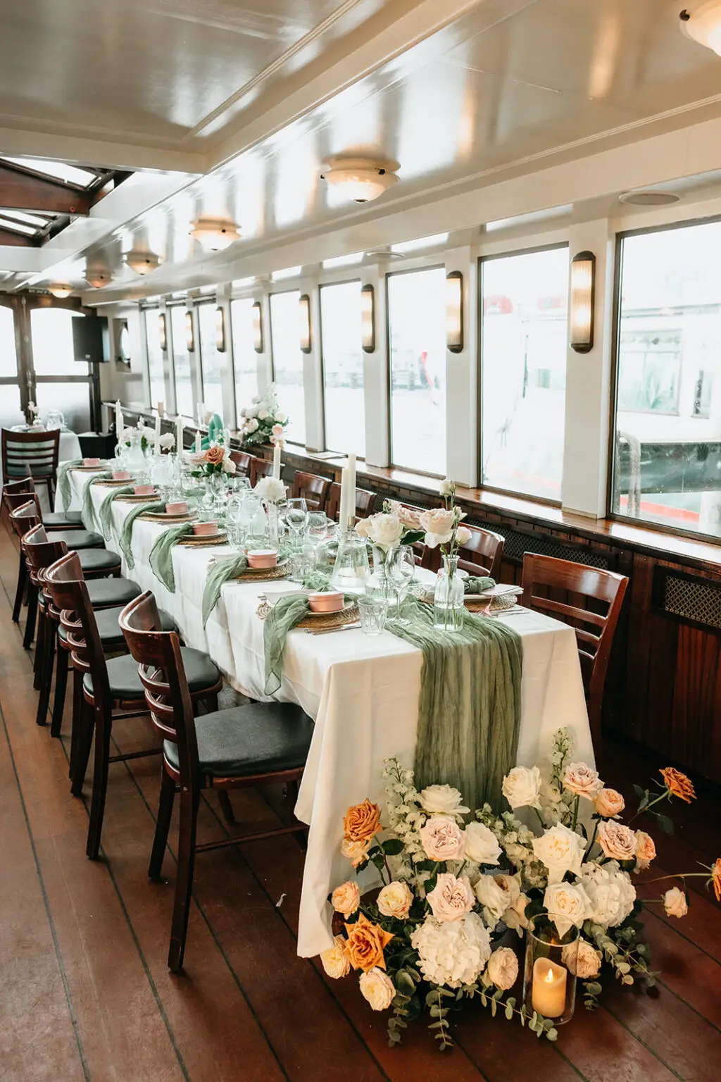 Long reception table decorated with flowers and candles aboard an Amsterdam canal boat for a destination wedding