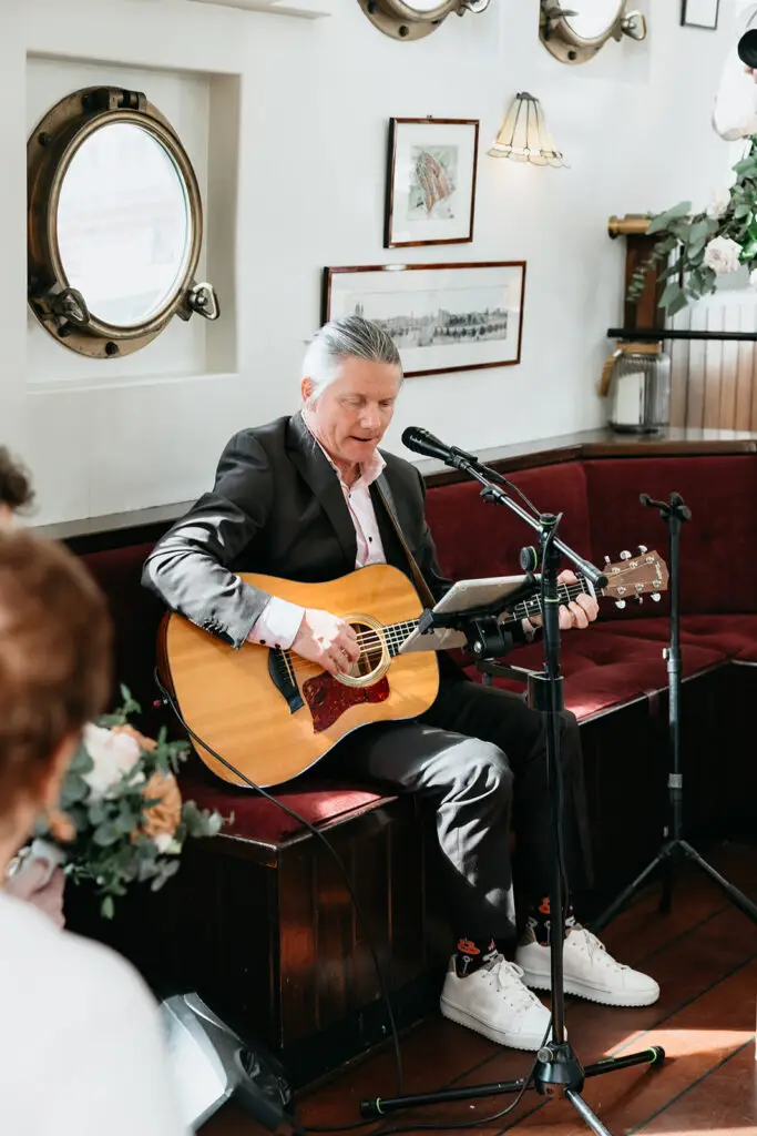 Musician performing live guitar music during a wedding ceremony aboard Het Wapen van Amsterdam