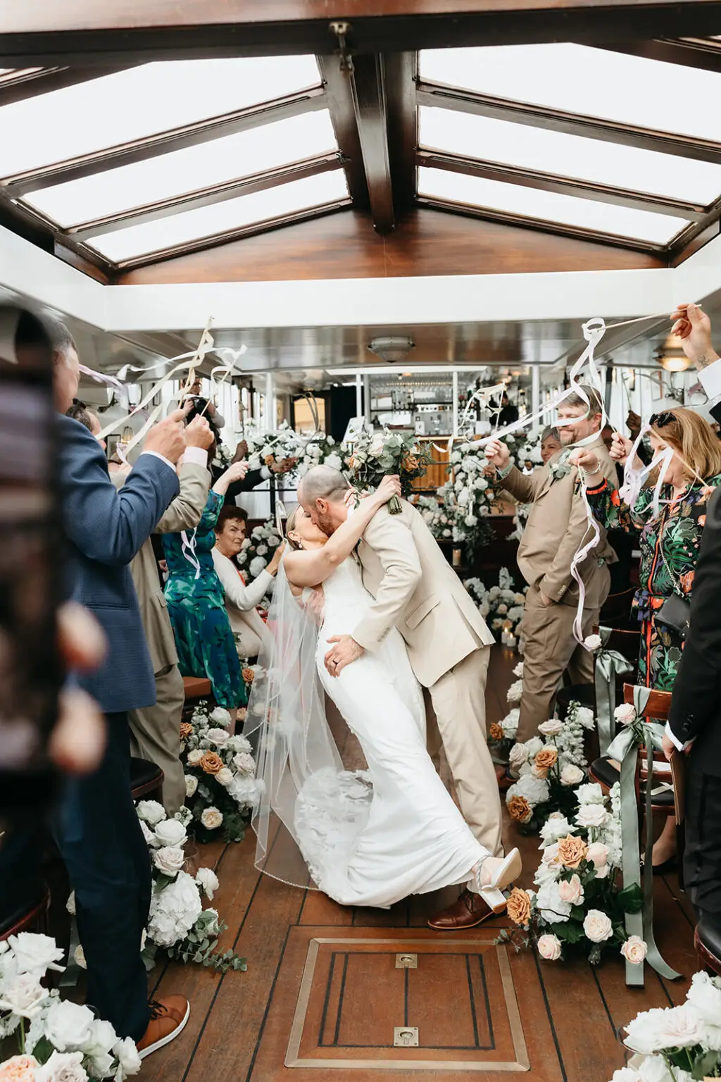 Bride and groom sharing their first kiss as guests celebrate aboard Het Wapen van Amsterdam