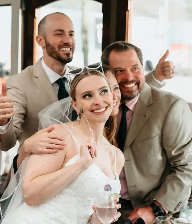 Bride smiling with wedding guests aboard an Amsterdam canal boat during a destination wedding celebration