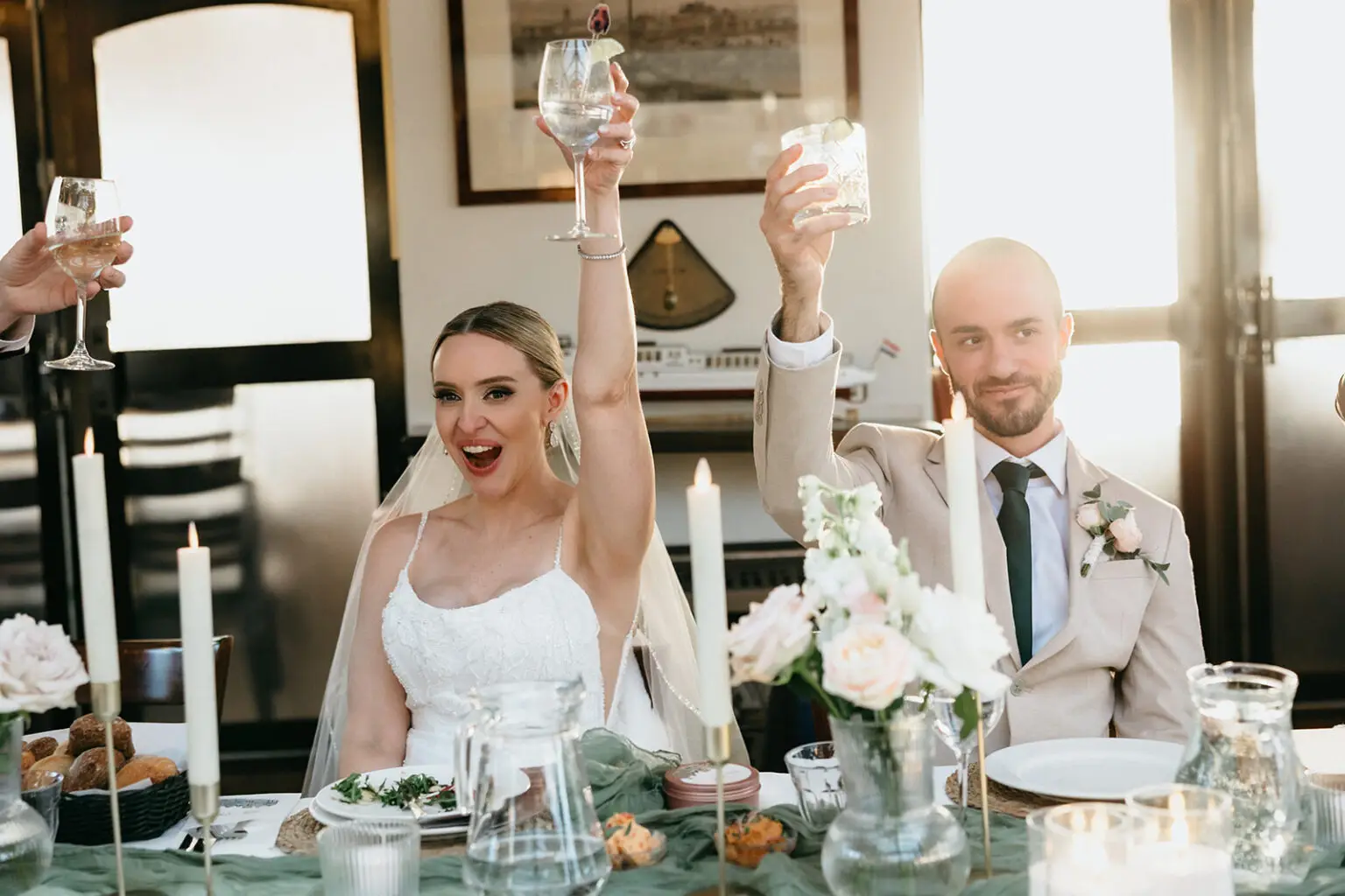 Bride and groom raising their glasses during a destination wedding reception aboard an Amsterdam canal boat