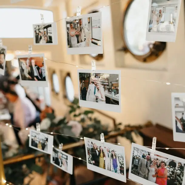 Printed wedding photographs displayed as reception décor during a destination wedding aboard an Amsterdam canal boat