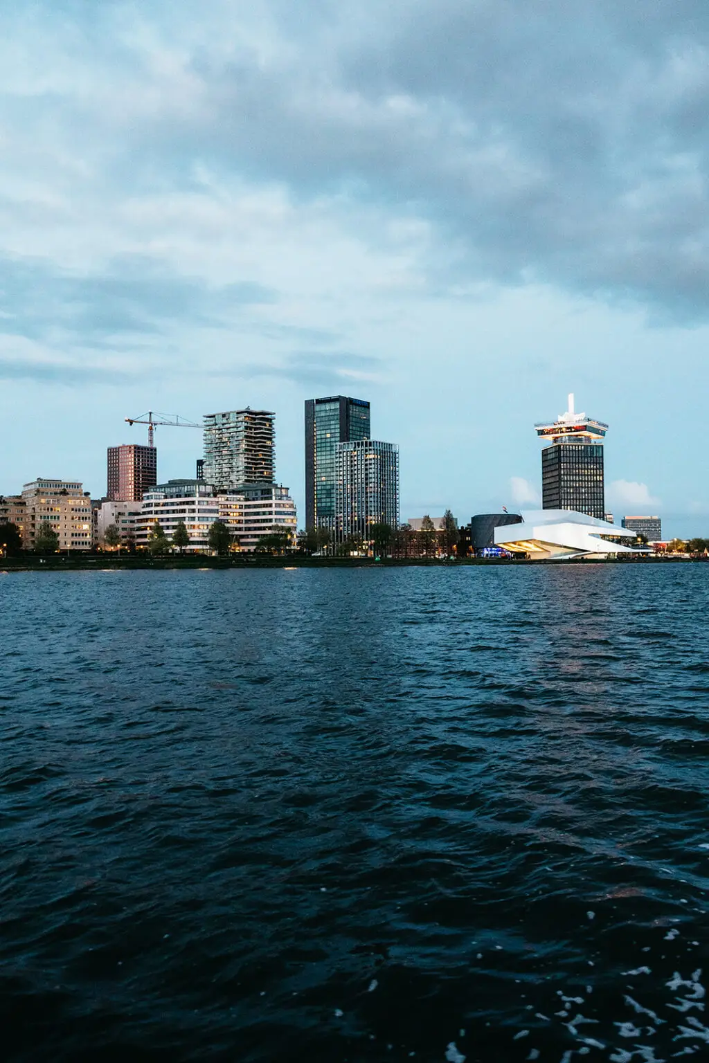 Amsterdam skyline viewed from the water at dusk during a destination wedding canal cruise