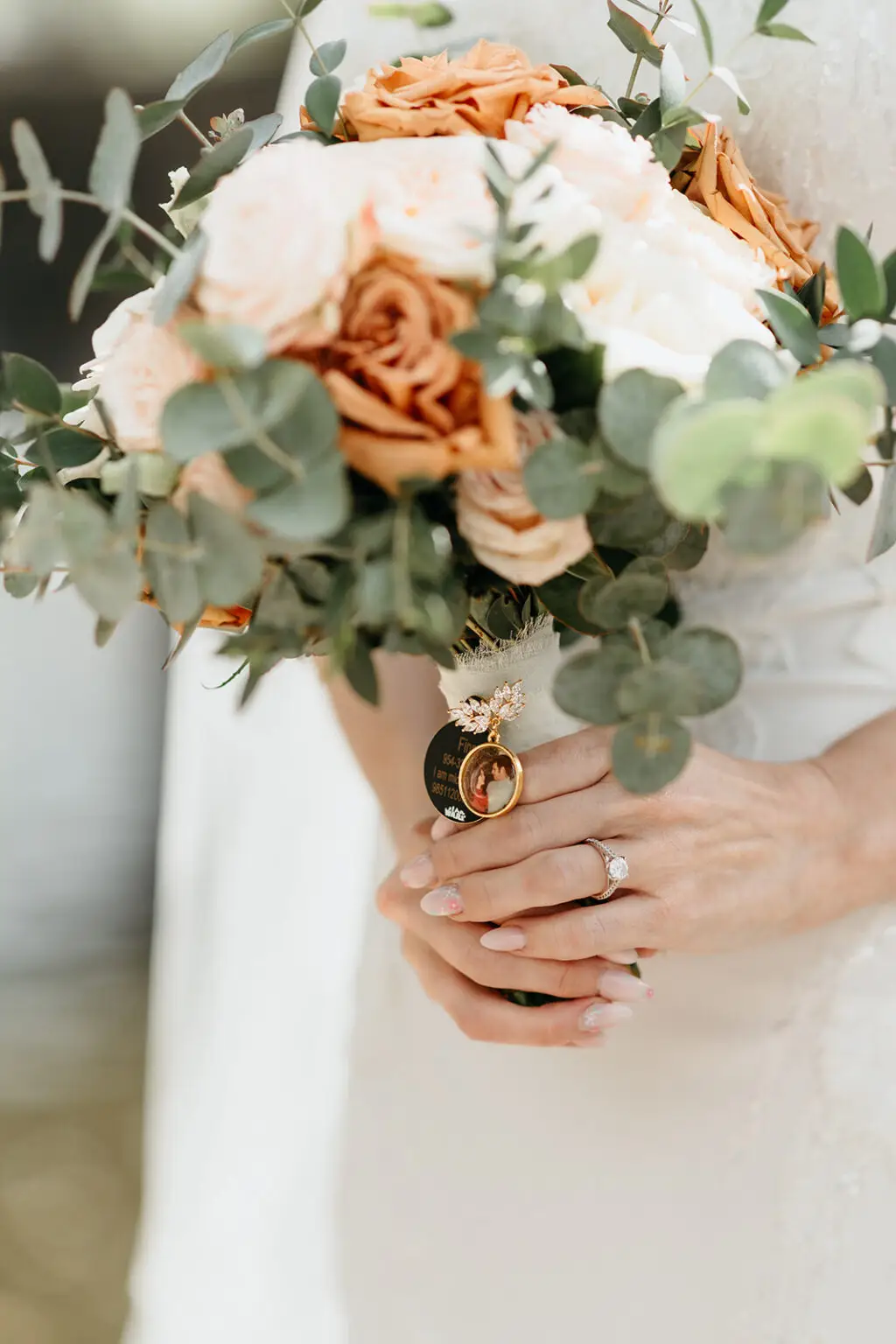 Bridal bouquet with soft peach roses, eucalyptus and wedding rings during portraits along the Amsterdam canals