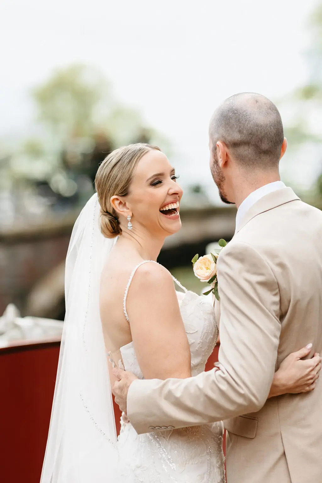 Bride laughing while embracing the groom aboard a classic wedding boat on the Amsterdam canals