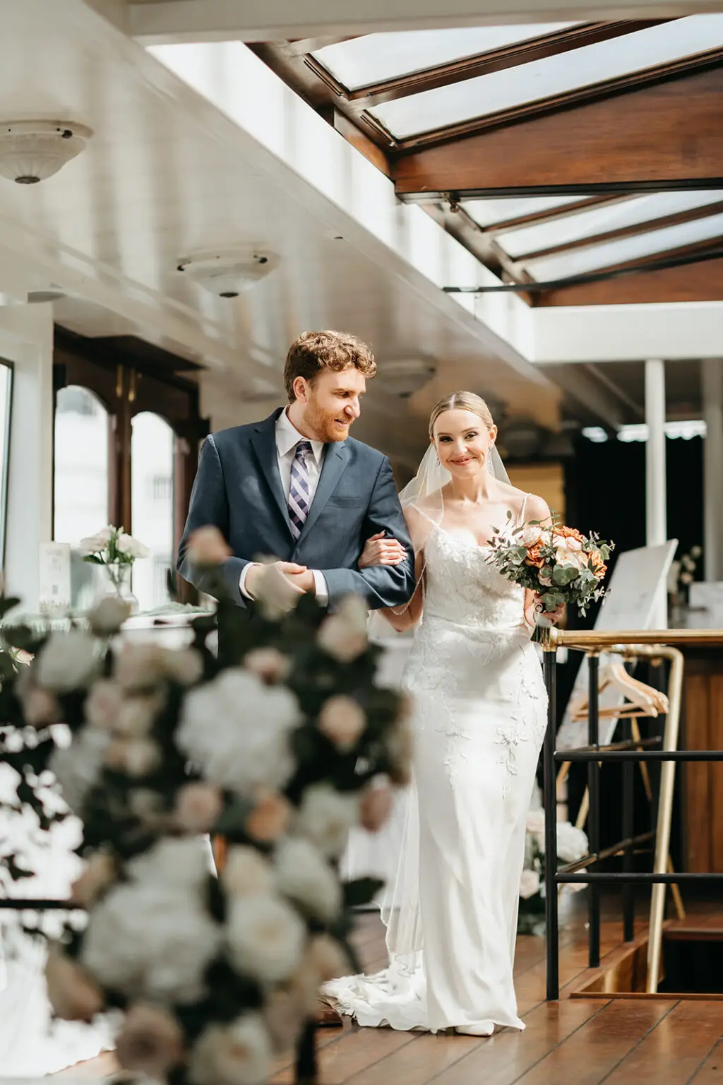 Bride walking down the aisle inside Het Wapen van Amsterdam accompanied by a family member