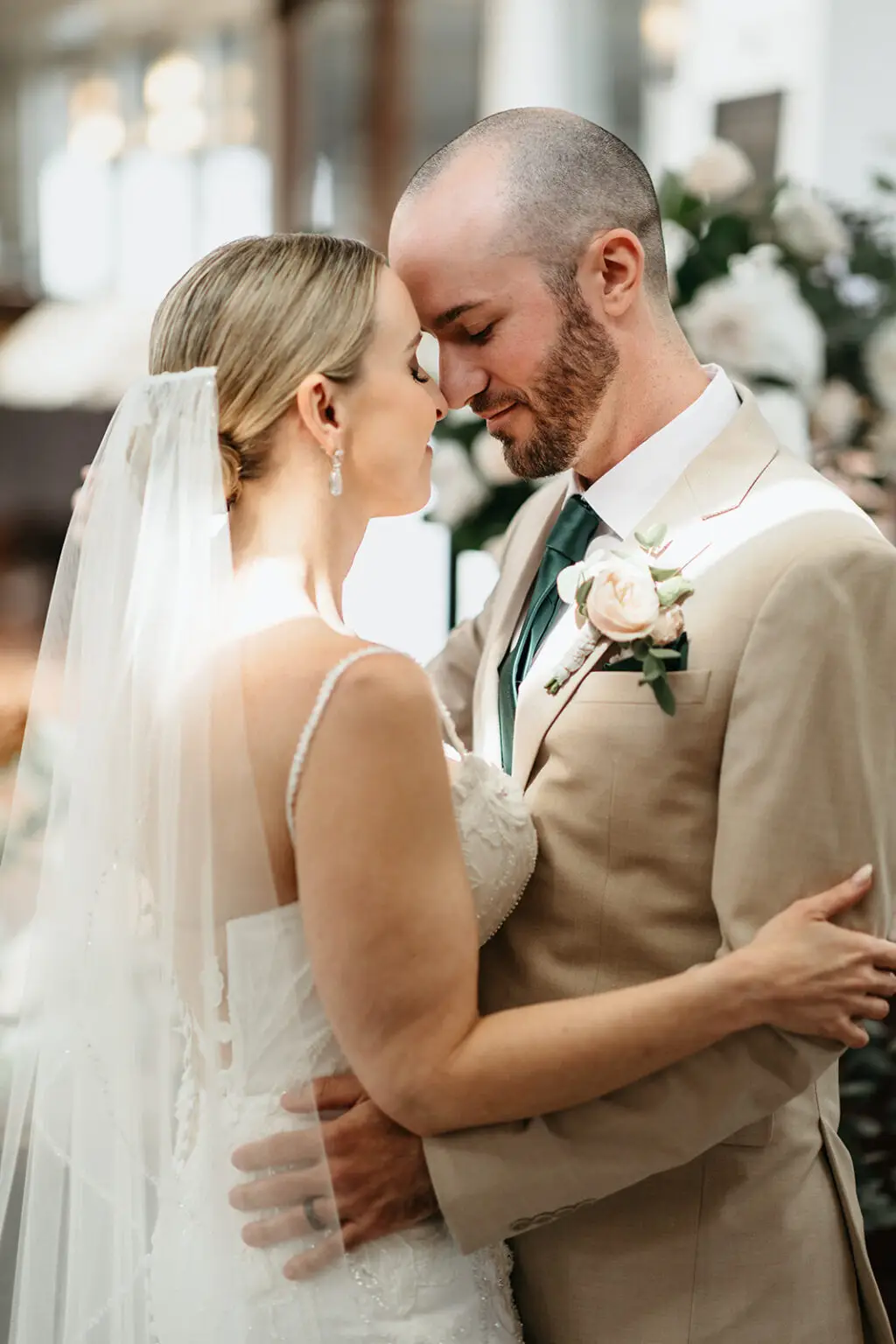 Bride and groom embracing after their ceremony inside Het Wapen van Amsterdam surrounded by elegant floral arrangements