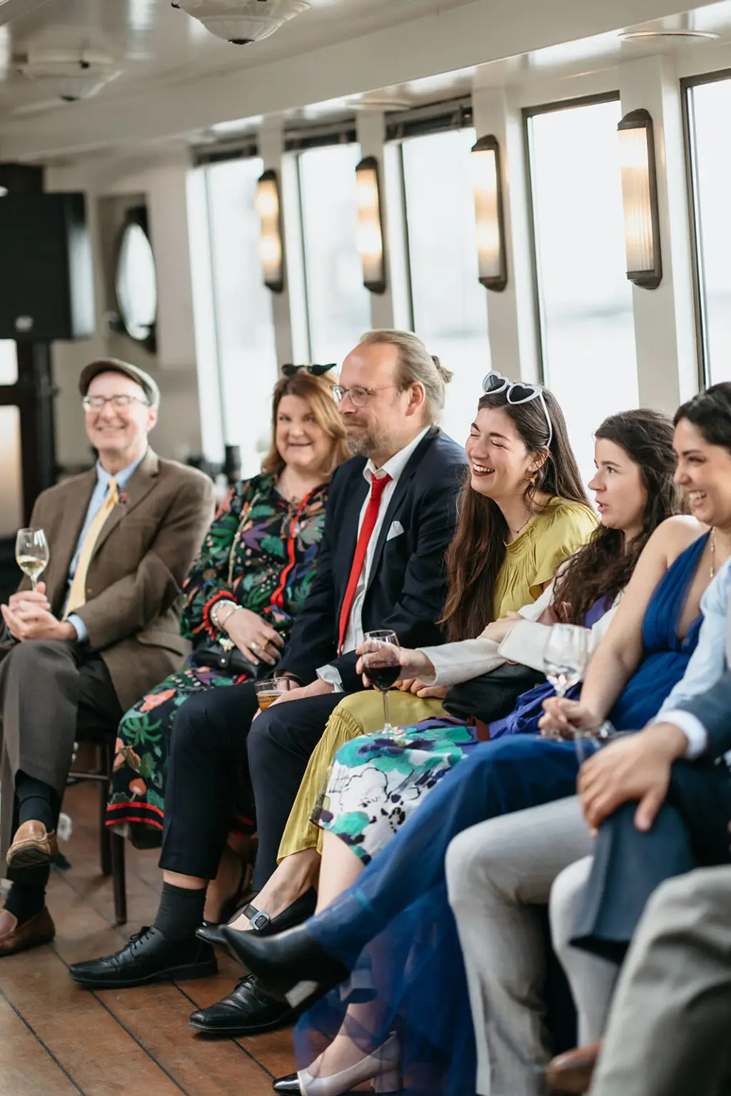 Wedding guests laughing during reception games aboard an Amsterdam canal boat at a destination wedding