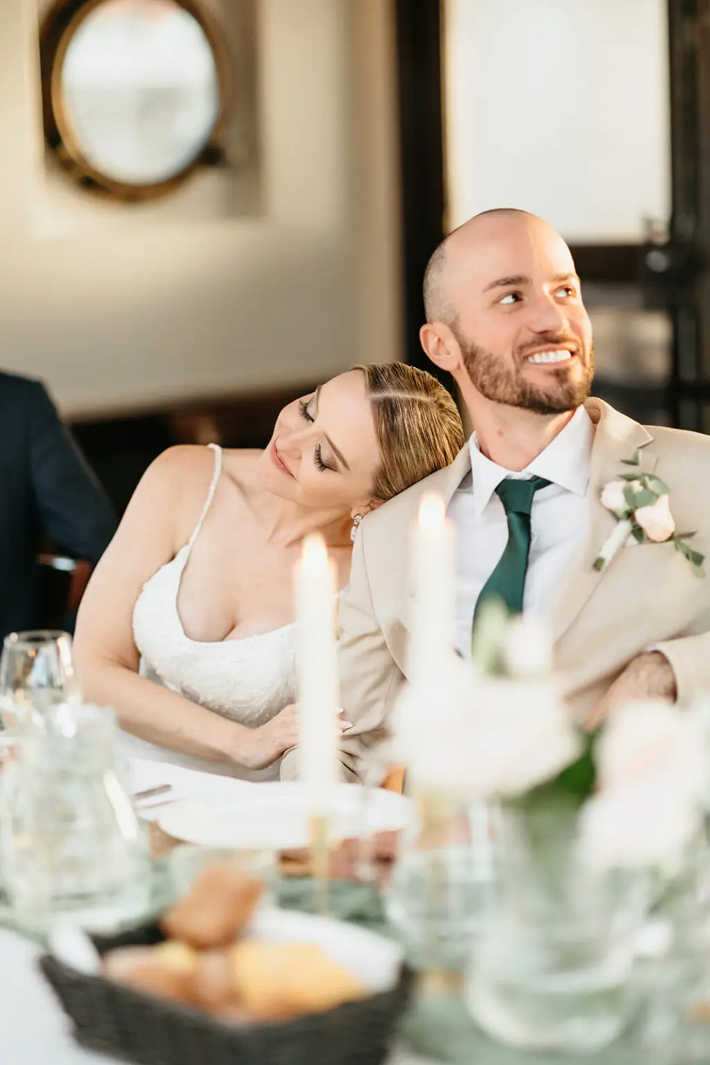 Bride resting on groom's shoulder while listening to speeches during an Amsterdam destination wedding reception
