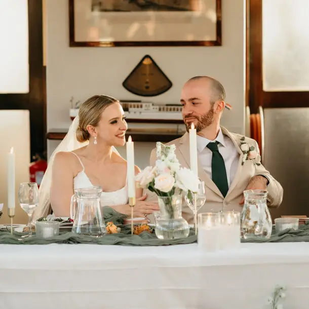 Bride and groom sharing a smile at their sweetheart table during a destination wedding reception aboard an Amsterdam canal boat