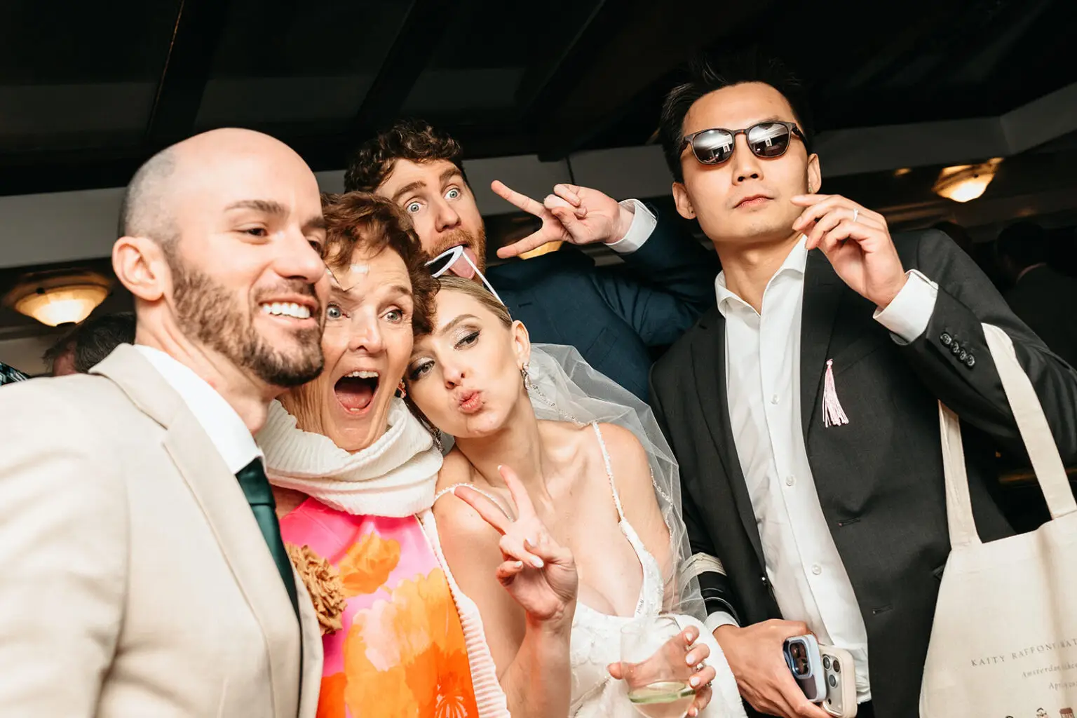 Bride, groom and wedding guests posing together during an Amsterdam canal wedding reception