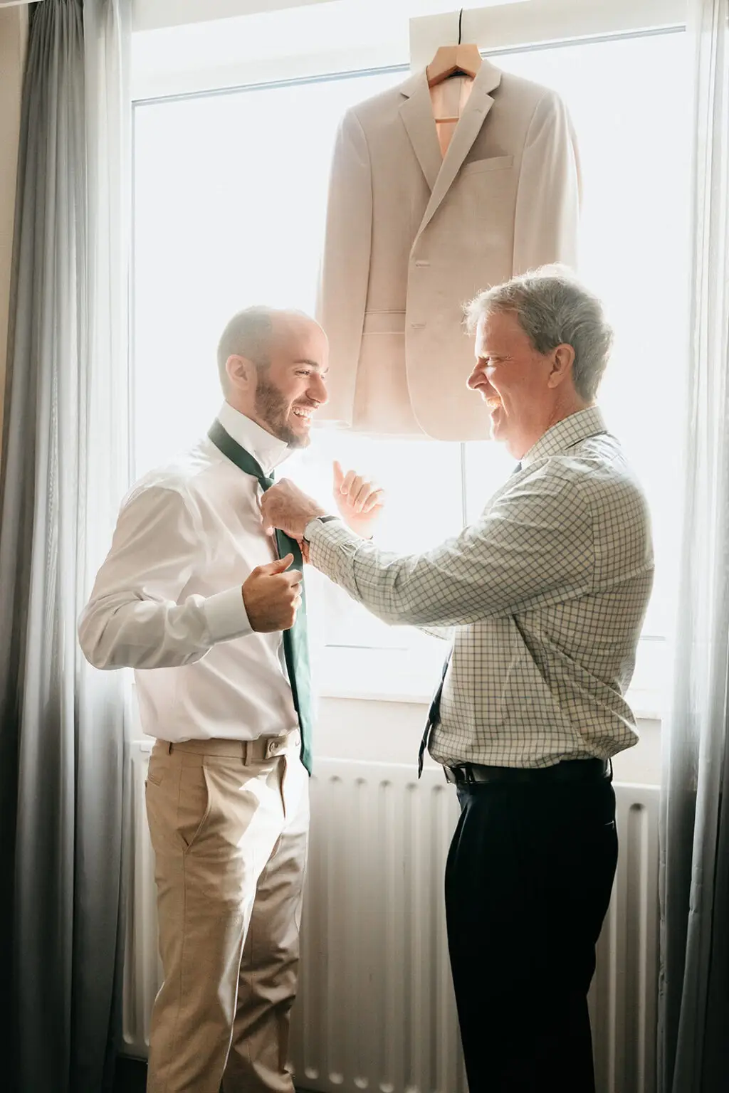 Groom adjusting his tie with a family member during morning preparations at Hotel De Witt in Amsterdam
